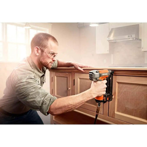 Person using Pneumatic 18 Gauge Brad Nailer Two And One Eighth Inch With Clean Drive Technology Plus Tool Bag on wooden cabinet