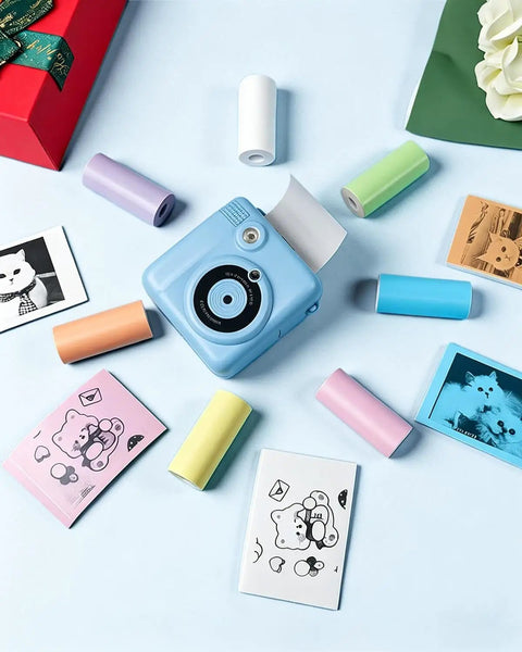 12 Pack BPA Free Instant Print Paper Refills For Kids Cameras, High Quality Thermal Paper Rolls With Glossy Finish, Non Sticky Tear Resistant And Jam Free, Easy Load For Crisp Clear Photo Prints Every Time. Blue kids camera with colorful thermal paper rolls and printed photos