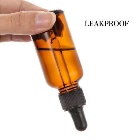 Twelve Knockout Amber Glass Dropper Bottles With Three Slick Stainless Steel Funnels And One Long Graduated Pipette Plus Twenty Four Waterproof Labels For Essential Oils And Hassle Free Beauty Blends, amber dropper bottle held in hand.