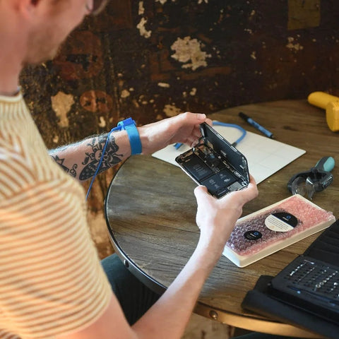 Person using portable ESD grounding mat for phone repair at home