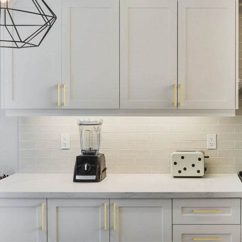 10 Pack Brushed Brass Cabinet Pulls With 9 Inch Hole Centers For Kitchen Cabinets Cupboards And Drawers Easy Install Heavy Duty Durable Zinc Alloy Construction With A Slick Timeless Finish ZH00013 installed on white kitchen cabinets above a countertop with a blender and toaster.