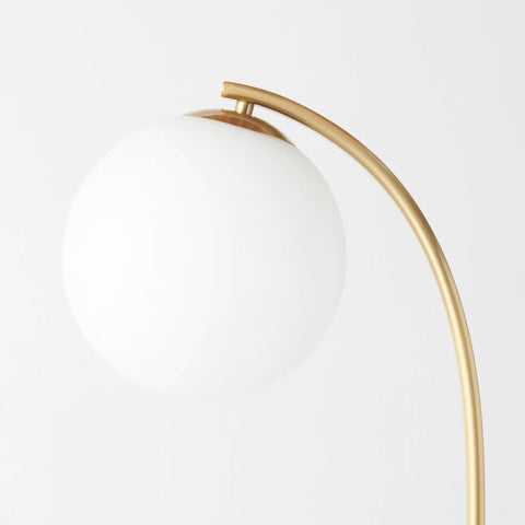 Close-up of frosted globe shade and brass arc of the Luna Drop 75 Inch Antique Brass Floor Lamp With Frosted White Glass Globe Shade.