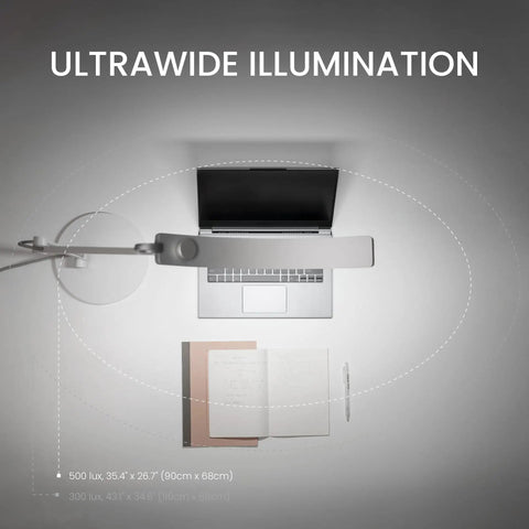 Ultrawide Desk Lamp With Eye Care Tech For Your Home Office Reading And Crafting Setup 13 Color Modes Dimmable Brightness Adjustable Arm Silver Finish 35 Inch Wide Desk Lighting Workspace Upgrade Lit showing top view illumination over laptop and book.