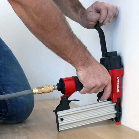 Heavy-Duty Pneumatic 18-Gauge Straight Brad Nailer Bad Boy in use, attaching trim near wall with aluminum magazine.