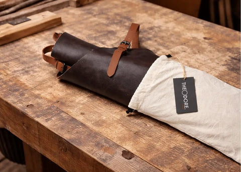 Genuine Leather Work Apron With CrossBack Straps For Woodworking Carpentry BBQ And Barista Tasks 3 Spacious Pockets And Fully Adjustable Fit Durable Brown Leather Apron For Studio Garage Or Kitchen Use rolled on a table
