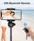 Person holding a Bluetooth remote with smartphone on tripod at the beach. Mini Portable Bluetooth Speaker 5.0 not visible.
