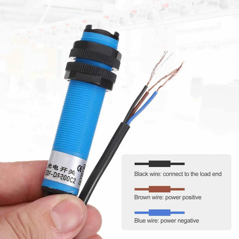 Hand holding Industrial Grade Photoelectric Sensor M18 Diffuse Reflection, Three-Line Detection Range 200cm, with wire connections visible