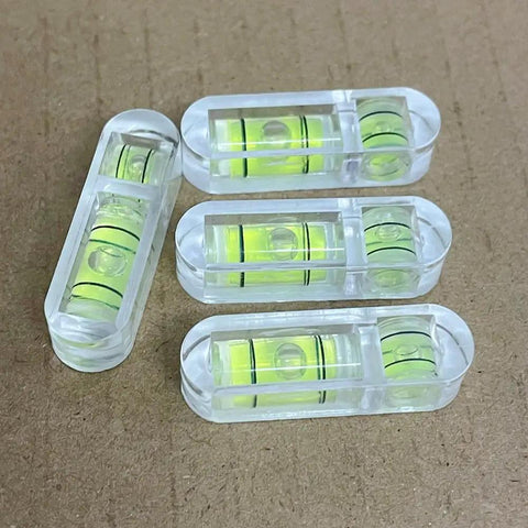 Tiny But Mighty 3 Pack Mini Bubble Spirit Levels Hella Compact Acrylic Measuring Tools on a brown background.
