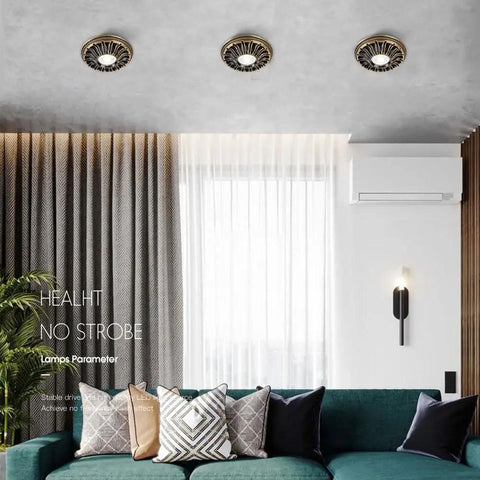 Three 4.5 Inch Solid Brass LED Recessed Downlights on ceiling in a modern living room, part of a Six Pack Top Shelf Led Can Lights.