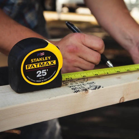 A person marking wood with FatMax 25 Foot Tape Measure 2 Pack Built Tough For Job Sites with 11 Foot Standout.