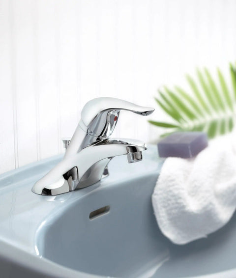 Chateau Chrome One-Handle Low Arc Centerset Bathroom Sink Faucet With Drain Assembly on a light blue sink.