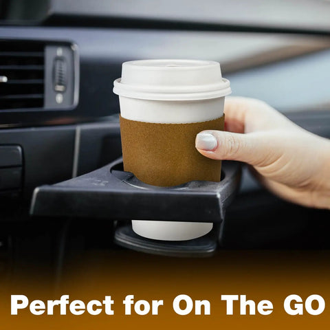 Hand placing Leak-Proof 12 Oz Coffee Cup with Lid and Sleeve into car holder, perfect for travel, spill-free.