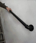 Person gripping a black metal handrail on a staircase for support.