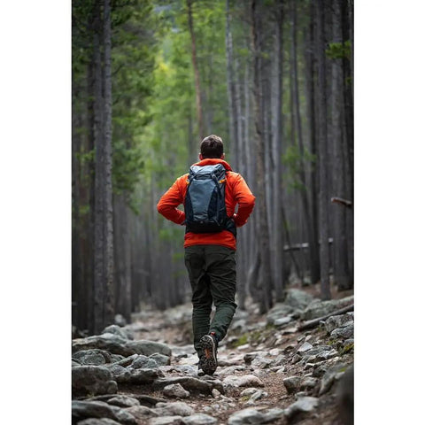 Hiker on rocky trail wearing PhotoSport 24L AW III Hiking Camera Backpack With Side Access And Removable Insert For Mirrorless Gear