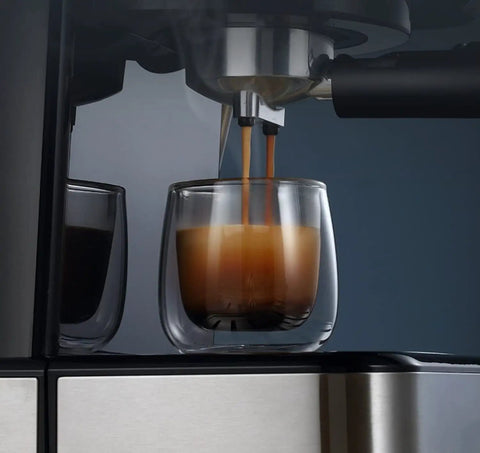 ROCK SOLID SEMI AUTOMATIC ESPRESSO MAKER BOASTS 20 BAR PRESSURE EXTRACTION AND A BUILDER GRADE STEEL STEAM WAND FOR HELLA RICH MILK FOAM PLUS INTUITIVE TEMPERATURE CONTROL AND 1050 WATT SILVER BUILD pouring espresso into a glass cup.
