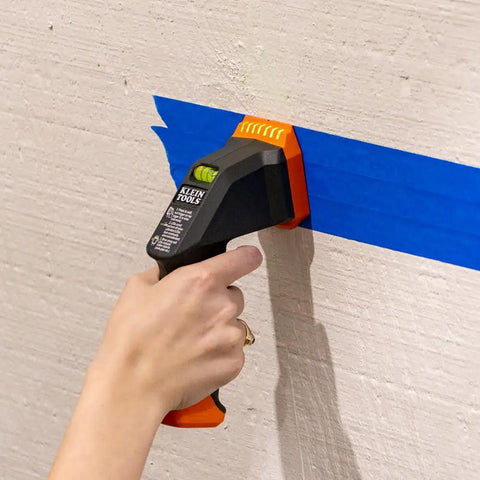 Hand using Dead On Electronic Stud Finder And Wall Scanner With Built In Bubble Level to locate studs on a wall.