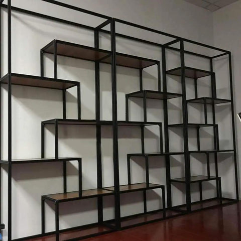Large black metal industrial shelving unit with multiple levels and wooden shelves against a wall