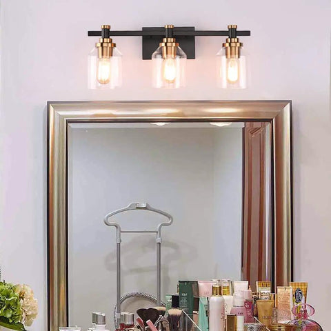 Three Light Industrial Bathroom Vanity Sconce With Black Gold Finish over a mirror, featuring clear glass shades.