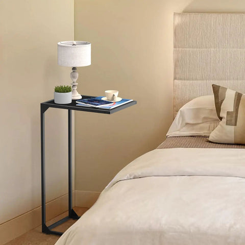Set Of 2 C Shaped End Tables That Slide Under The Sofa For Easy Laptop Work Or Snack And Drink Tray And TV Tray Space Saving Black Living Room And Bedroom Couch Side Tables in bedroom with lamp and books.