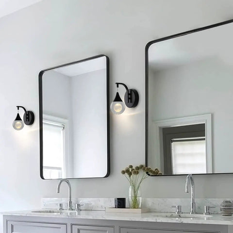 Moon Crystal LED Wall Sconce With Dimmable 5W Light in modern matte black beside bathroom mirrors and sinks.