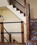 Wooden staircase with black railing and decorative tiles, featuring a warm interior aesthetic and ample light.