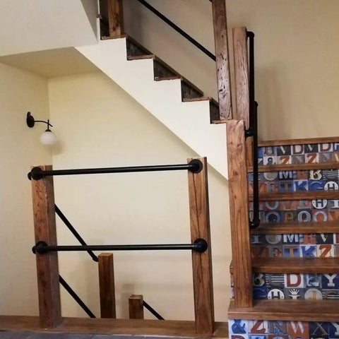 Wooden staircase with black railing and decorative tiles, featuring a warm interior aesthetic and ample light.
