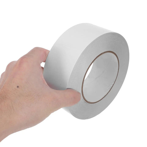 Hand holding a roll of Slick Heavy Duty Double Sided Tape For Quick Fixes And Secure Mounting Reusable Transparent Adhesive Roll.