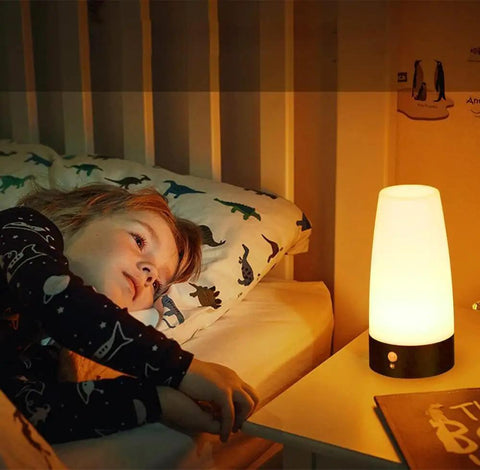 Child in bed with Retro LED Night Light With PIR Motion Sensor on nightstand, glowing softly in a kids room.