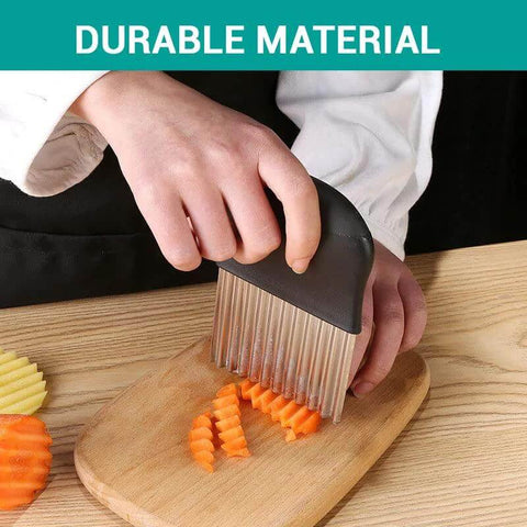 Front view of black-handled stainless steel crinkle cutter slicing carrot sticks on a wooden cutting board