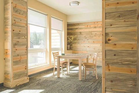 Room with wooden walls and windows, featuring gray vinyl wall base 6 inch 20 feet with strong peel and stick adhesive baseboard trim.