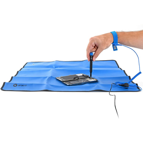 Portable ESD grounding mat with wrist strap and grounding cord for electronics repair, showcasing anti-static protection in use.