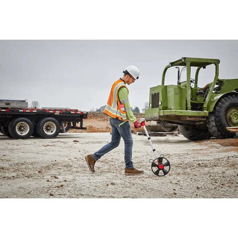 Hella Precise 12 Inch Digital Measuring Wheel With IP54 Rated Housing And Vivid Backlit Display used by a worker on construction site.
