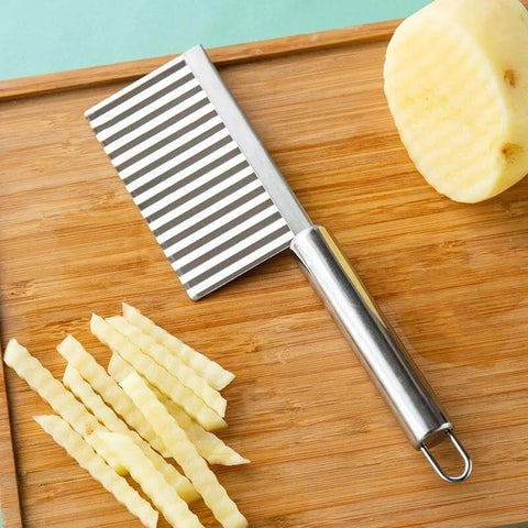 Front view of stainless steel vegetable and fruit wavy crinkle cutter on wooden cutting board.