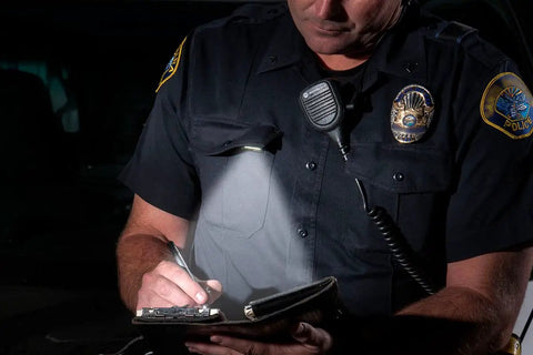 Hands Free LED Pocket Light Clip On For Shirts And Molle 160 Degree Adjustable LED Arm illuminating a notebook during night use.