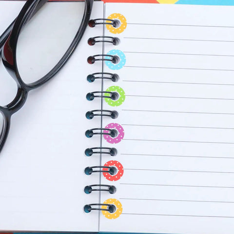 Heavy Duty Hole Punch Reinforcement Stickers Six Sheets For Loose Leaf Paper Fixes That Patch Broken Ring Bindings And Keep Your Class Notes Intact With No Sweat This Semester on a notebook with colorful rings.