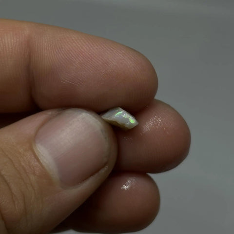 Holding a small piece of Raw Opal Cutting Material From Coober Pedy Multicolor Barred Opal Stone Light And Dark For Jewelry Making