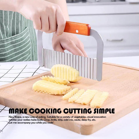 Side view of stainless steel wavy crinkle cutter with wooden handle cutting potato on a wooden board