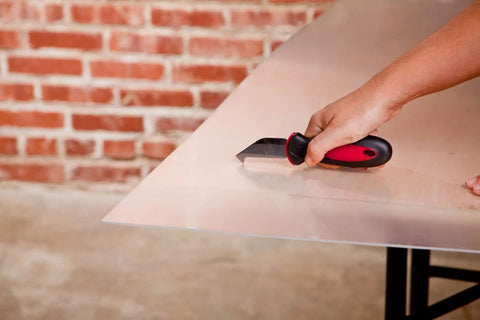 Person using Pro Grade Plexiglass Scoring Tool With Ultra Sharp Steel Blade For Precise Grooves In Plexiglass Acrylic And Plastic on a sheet.