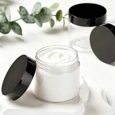12 Pack 4 Oz Clear Plastic Sample Jars With Heavy Duty Black Screw Top Lids filled with white cream, perfect for travel or cosmetics.