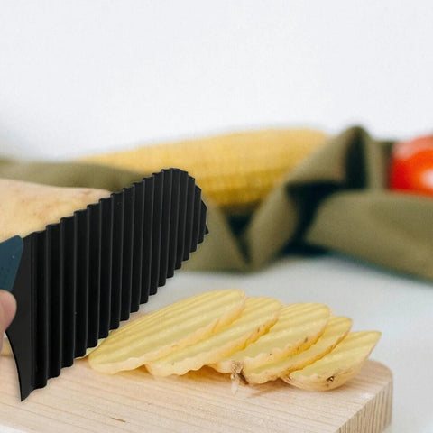 Potato crinkle cutter, black, close-up view slicing potatoes on a wooden cutting board
