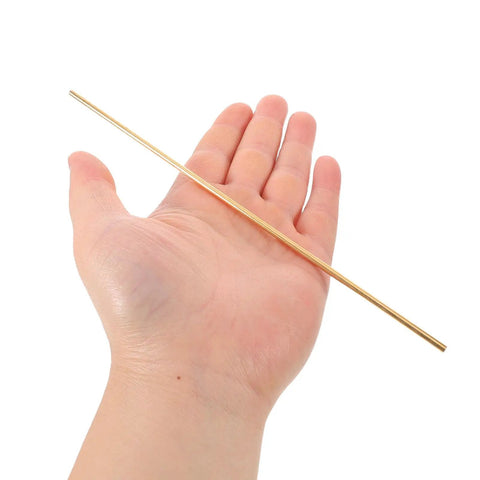 Hand holding one of two brass knife pins for DIY knife handle kits and repairs, solid round dowels with corrosion resistance