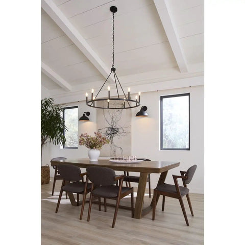 Modern dining room with wooden table, six chairs, and large black chandelier under vaulted ceiling with natural light.