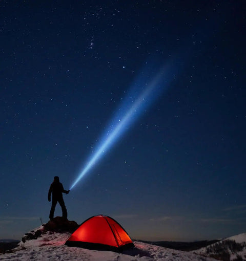 Person with Heavy Duty Tactical LED Flashlight, 3 Cell D Power, Coyote Tan, illuminating a red tent and night sky on a snowy hilltop