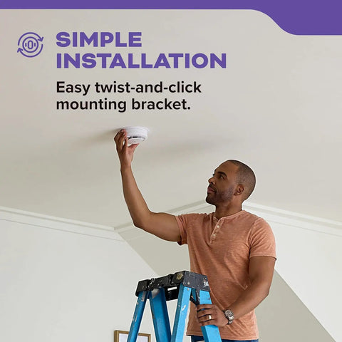 Man installing hardwired smoke and carbon monoxide alarm with battery backup, interconnectable, dual detection on ceiling