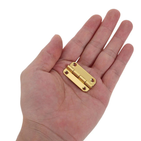 Close-up of hand holding one Vintage Small Iron Cabinet Hinges 12 Pack With Rounded Corners And Four Hole Vertical Design Antique Gold Finish