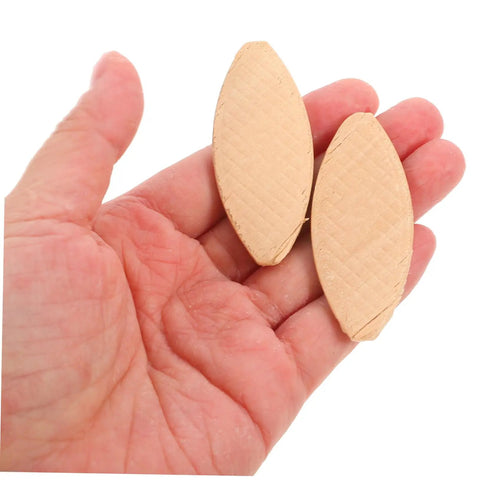 Top Shelf Wood Joining Biscuits And Joint Plates For Zero Hassle Furniture Assembly in a hand, light yellow hardwood cutouts for alignment.