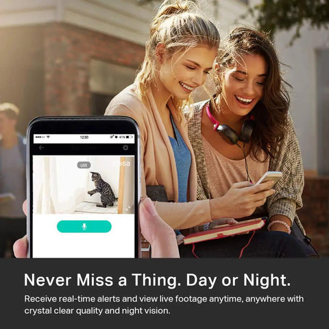 Two women looking at a smartphone displaying 1080p Indoor Wired Security Cam For Home Surveillance, Real Time Motion And Sound Alerts app