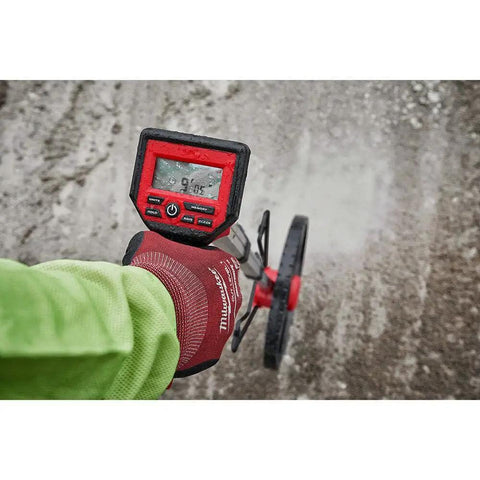 Hella Precise 12 Inch Digital Measuring Wheel With IP54 Rated Housing and vivid backlit display in use on gravel surface.