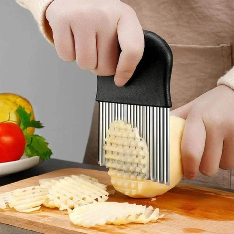 Crinkle cutter knife with black handle and stainless steel ribbed blades slicing a potato into crinkle fries.