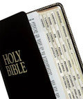 Slick Gold Edged Self Adhesive Bible Tabs For Old And New Testament Plus Catholic Books Quick Reference Page Markers in a black Bible.